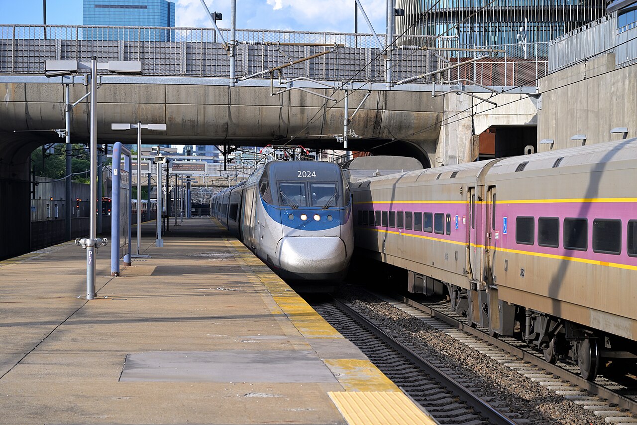 A next-generation Acela pulling in next to the MBTA Purple Line.